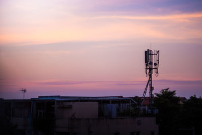 Silhouette communications tower against sky during sunset