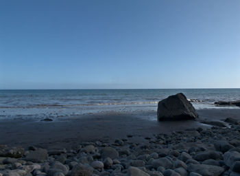 Rocks on beach against clear sky