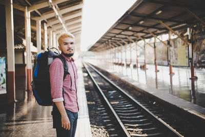 Portrait of young man standing at railroad station platform