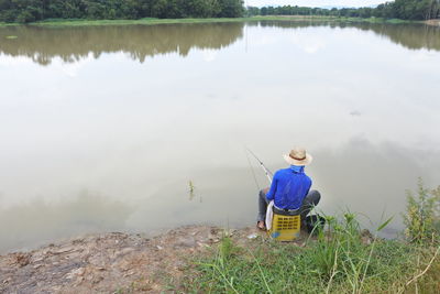 Rear view of man sitting at lakeshore