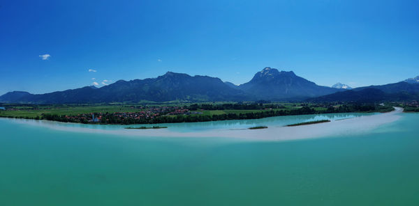 Scenic view of lake and mountains against blue sky