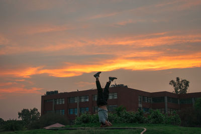Man by woman against orange sky