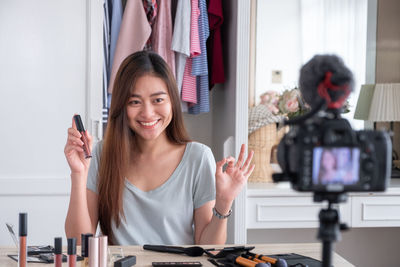 Smiling beautiful woman making video of beauty products at home