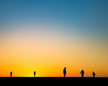 Silhouette people on landscape against clear sky during sunset