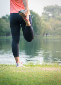 Low section of woman standing by lake