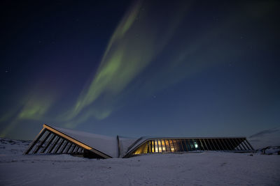 Nightshot of icefjord center in snowy surounding and aurora borealis above