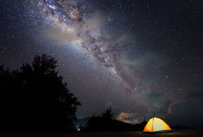 Illuminated tent on field against sky at night