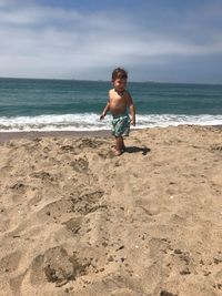 Full length of shirtless boy standing on sandy beach