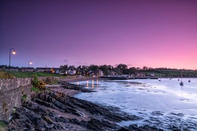 Panoramic view of illuminated city against clear sky at sunset