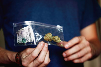 Midsection of man holding marijuana in plastic bag