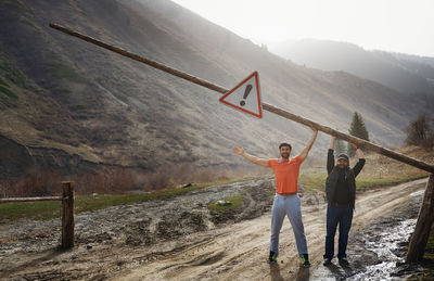 Two men opening wooden barrier on a country road