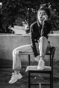 Woman looking away while sitting on bench in park