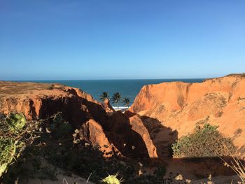 Scenic view of rocks in sea against clear blue sky