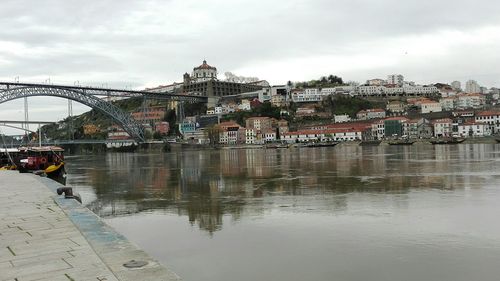 Bridge over river in city against sky