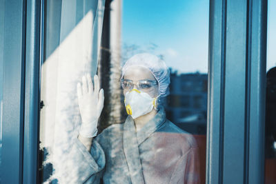 Woman wearing protective workwear seen through glass window