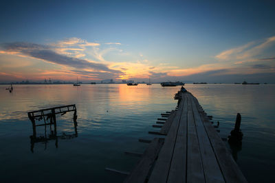 Pier over lake against sky during sunset