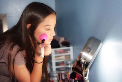 Young woman applying make-up at home