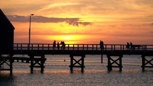 People on pier at sunset