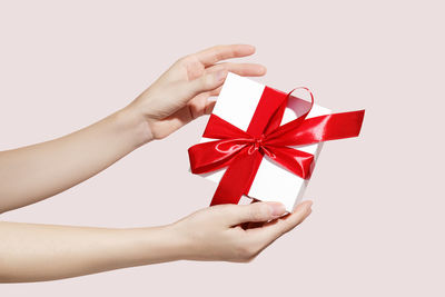 Cropped hands of woman holding gift box against white background