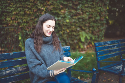 Woman reading a book on the bench in a park