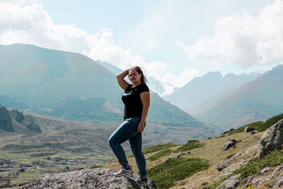 Portrait of woman standing on rock against mountain range