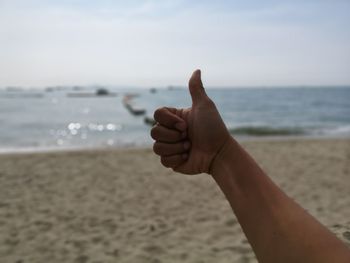 Midsection of person on beach against sky