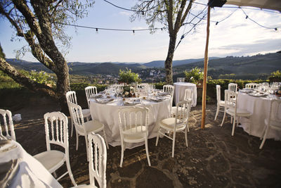 Empty chairs and tables at restaurant against sky