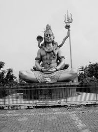 Statue of boy sitting against sky