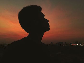 Close-up of silhouette man with cityscape against sky during sunset