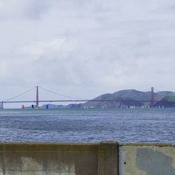 Bridge over river against cloudy sky