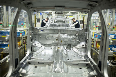 Two colleagues working in modern car factory