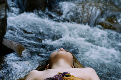 Close-up of woman lying on rock by river