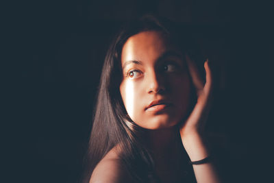 Portrait of a beautiful young woman over black background