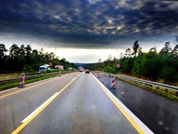 Cars on road against cloudy sky