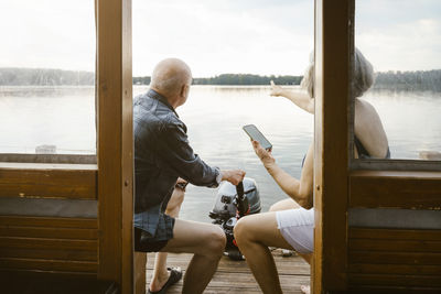 Senior couple with smart phone sitting on houseboat