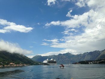 Boats sailing in sea against cloudy sky