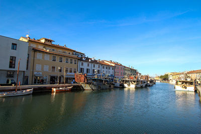 Boats moored in leonardo da vinci canal by buildings in city against sky