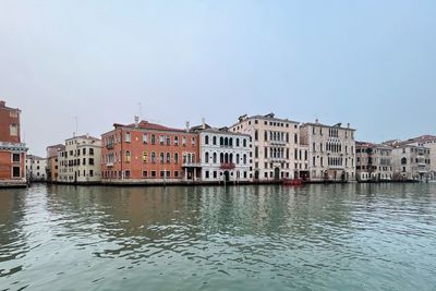 Buildings by river against clear sky