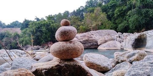 Stone stack on rock by river against sky