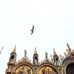 Low angle view of birds flying against clear sky