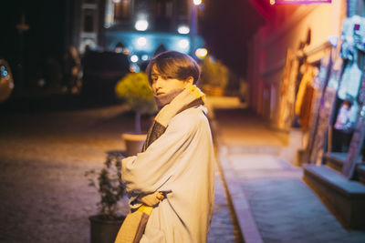 Side view of woman standing on street at night