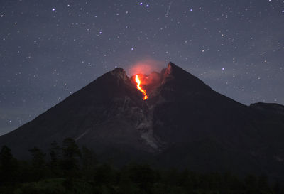 Low angle view of volcano against sky at night