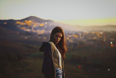 Portrait of young woman standing against sky during sunset