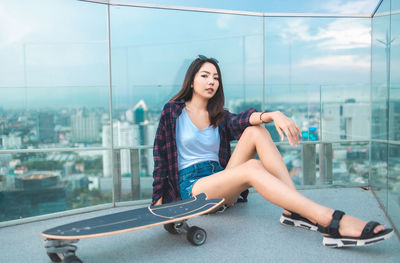 Beautiful young woman sitting against built structure