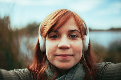 Close-up portrait of young woman listening music through headphones