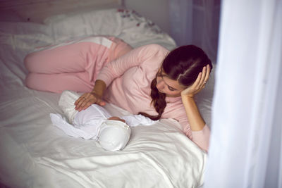 Mom with a small newborn daughter lying on the bed in the bedroom