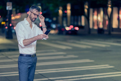 Full length of man using mobile phone on street