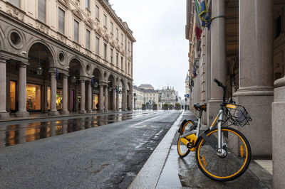 Bicycle by street against buildings in city