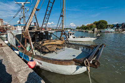 Sailboats moored on harbor against sky