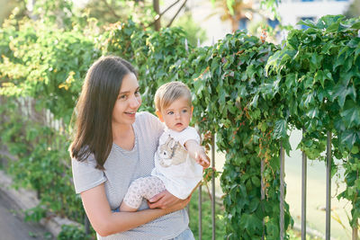 Portrait of woman with daughter against plants